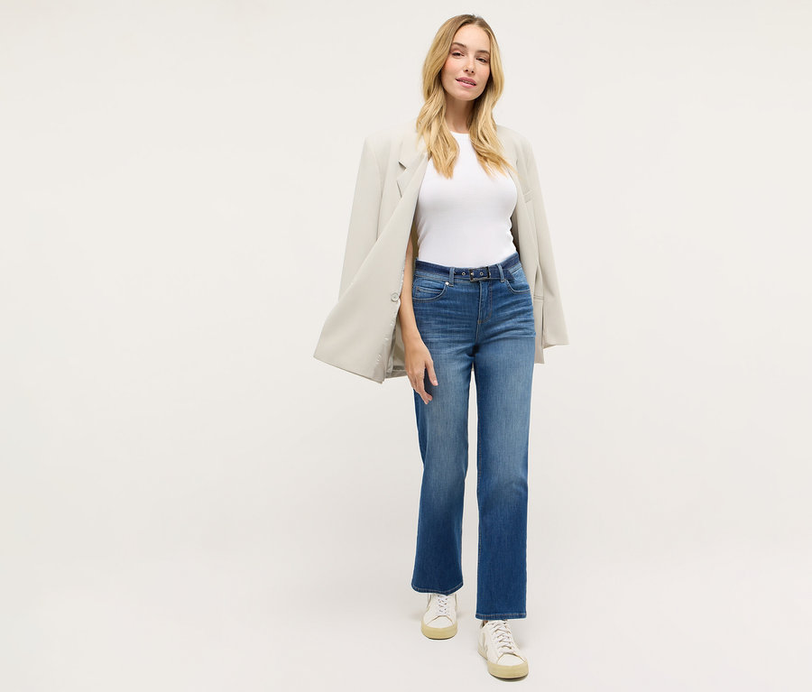 Femme portant un jean droit « Lara City » Angels, un t-shirt blanc, un blazer et des baskets.
