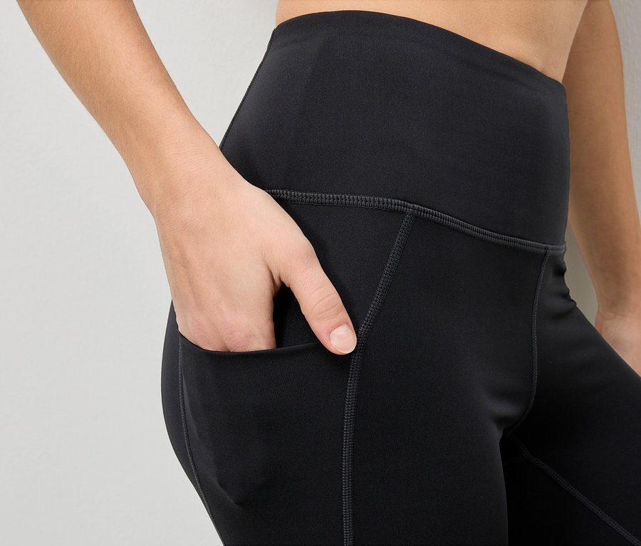 Femme mettant la main dans la poche d'un legging noir.