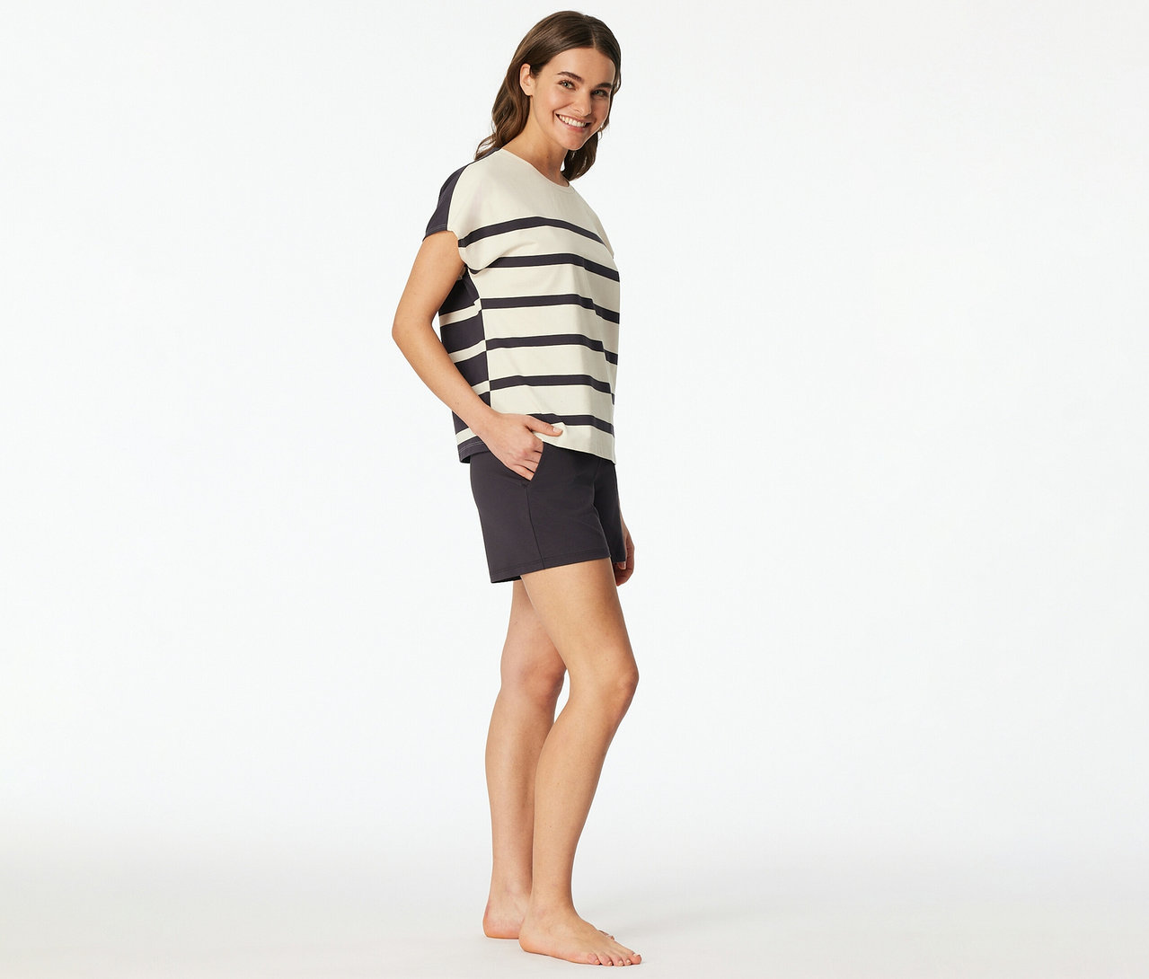 Femme portant un set shorty SCHIESSER avec un haut rayé et un short foncé, souriant, la main dans la poche.