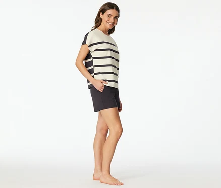 Femme portant un set shorty SCHIESSER avec un haut rayé et un short foncé, souriant, la main dans la poche.