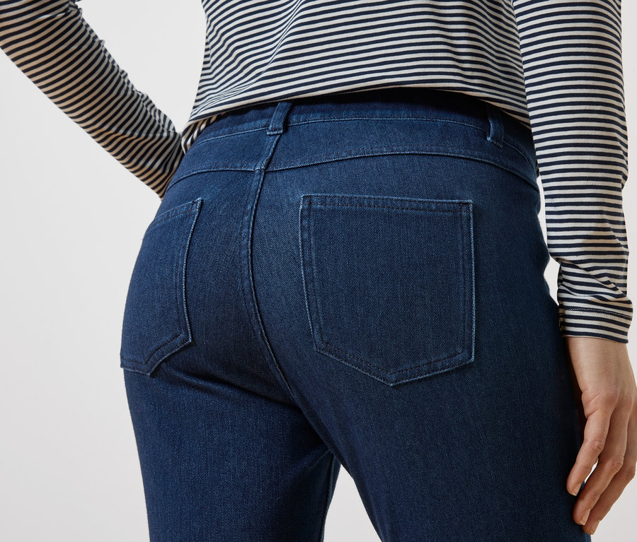 Vue arrière d'une personne portant un jean bleu foncé et un haut rayé.