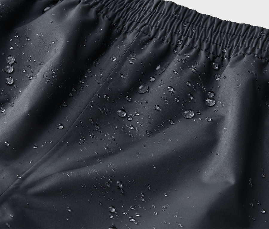 Gros plan d'un pantalon noir imperméable avec une taille élastique et des gouttes d'eau.