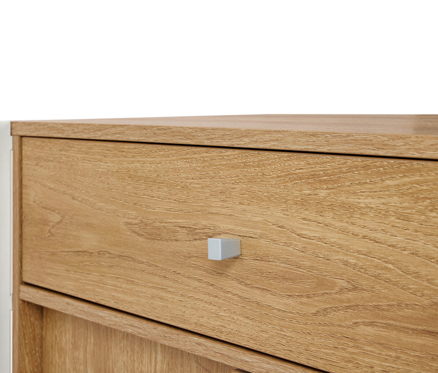 Gros plan d'une commode en bois marron clair avec une poignée argentée.