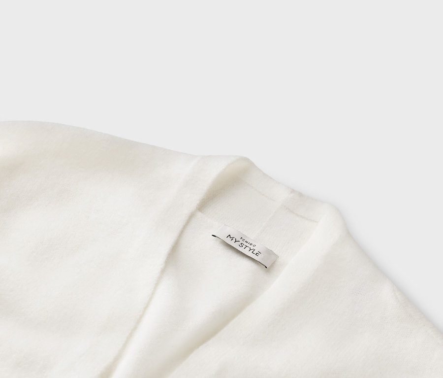 Gros plan sur un cardigan en tricot blanc avec une étiquette portant l'inscription « TCHIBO MY STYLE ».