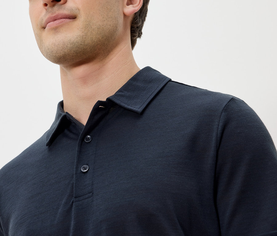 Gros plan d'un homme portant un polo bleu marine.