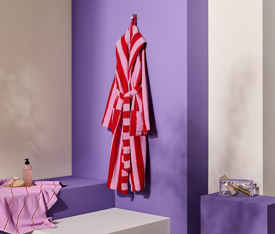 Peignoir rayé accroché à un crochet à côté d'une serviette, du savon et d'une trousse de toilette.
