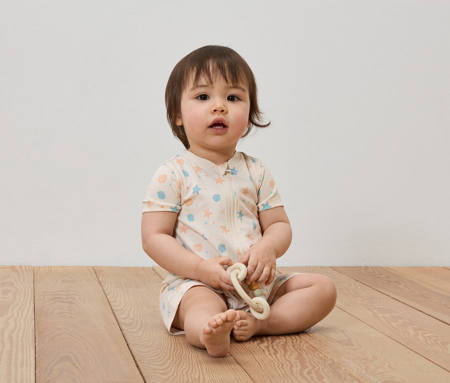 Un bébé est assis sur un plancher en bois et tient un jouet.