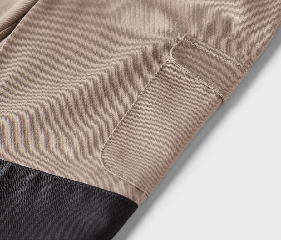 Gros plan d'un pantalon beige avec une poche plaquée et une partie inférieure noire.