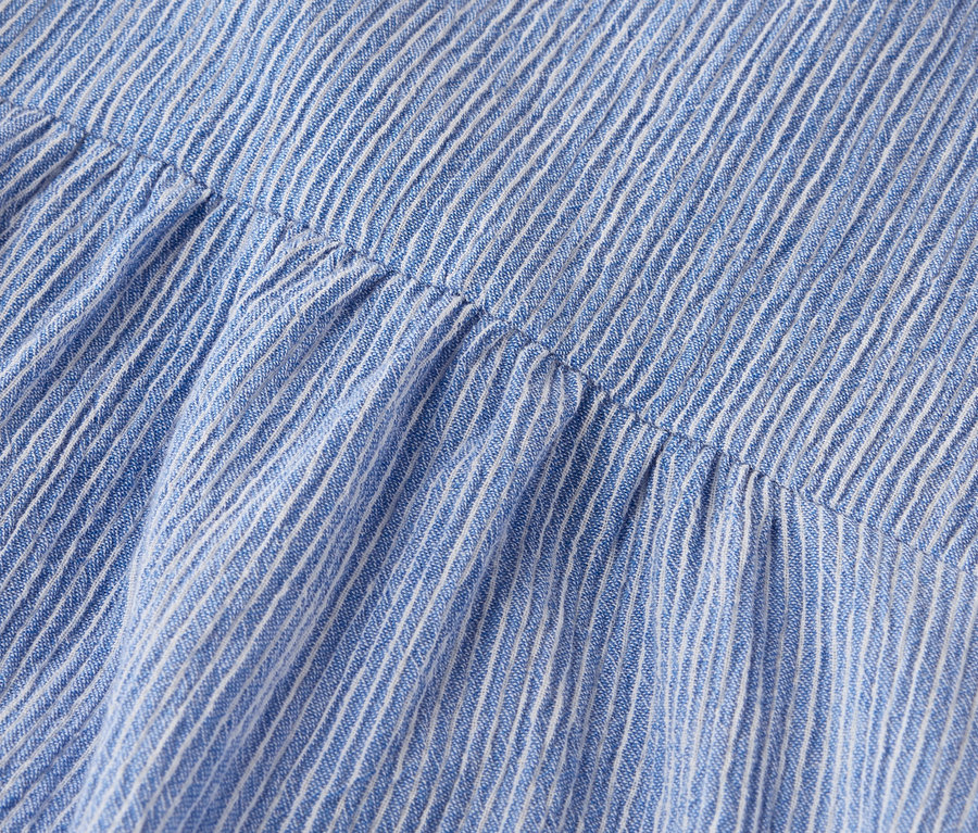 Gros plan d'un tissu rayé bleu et blanc avec des détails froncés.