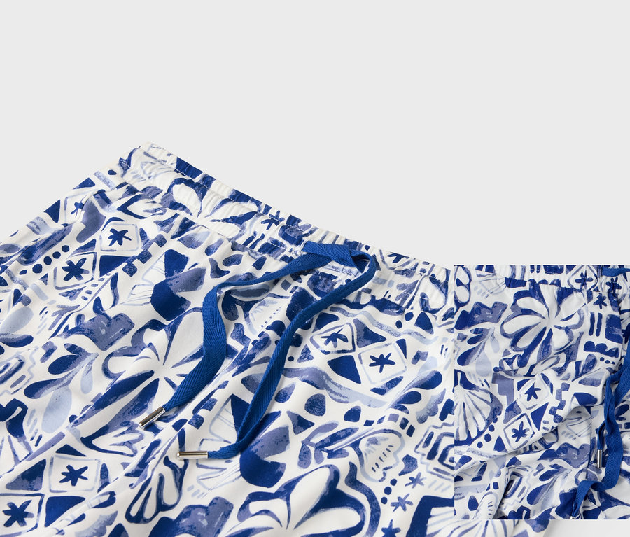 Gros plan sur le haut d'un short blanc avec un motif bleu et un cordon de serrage bleu.