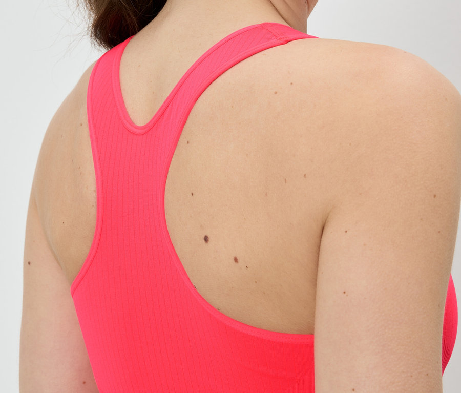 Gros plan sur le dos d'une femme portant un haut de sport rose avec dos nageur.