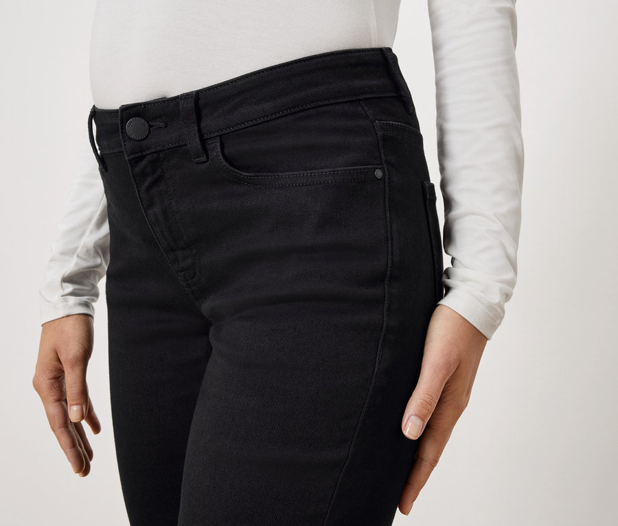 Gros plan d'une personne portant un jean noir et un haut blanc à manches longues.