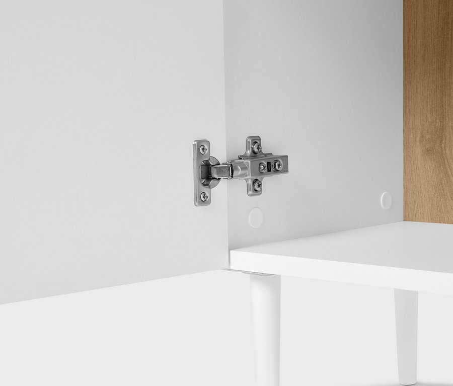 Gros plan d'une armoire avec une charnière argentée sur une porte blanche.