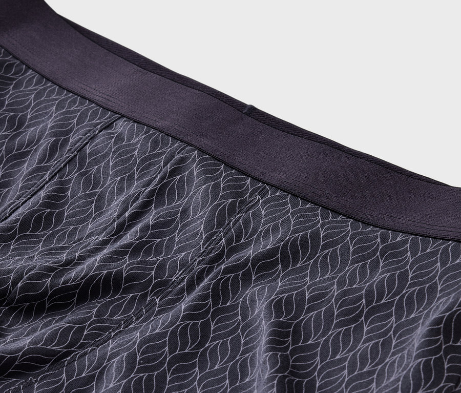 Gros plan sur un boxer gris foncé avec un motif de feuilles blanches et une ceinture gris foncé.