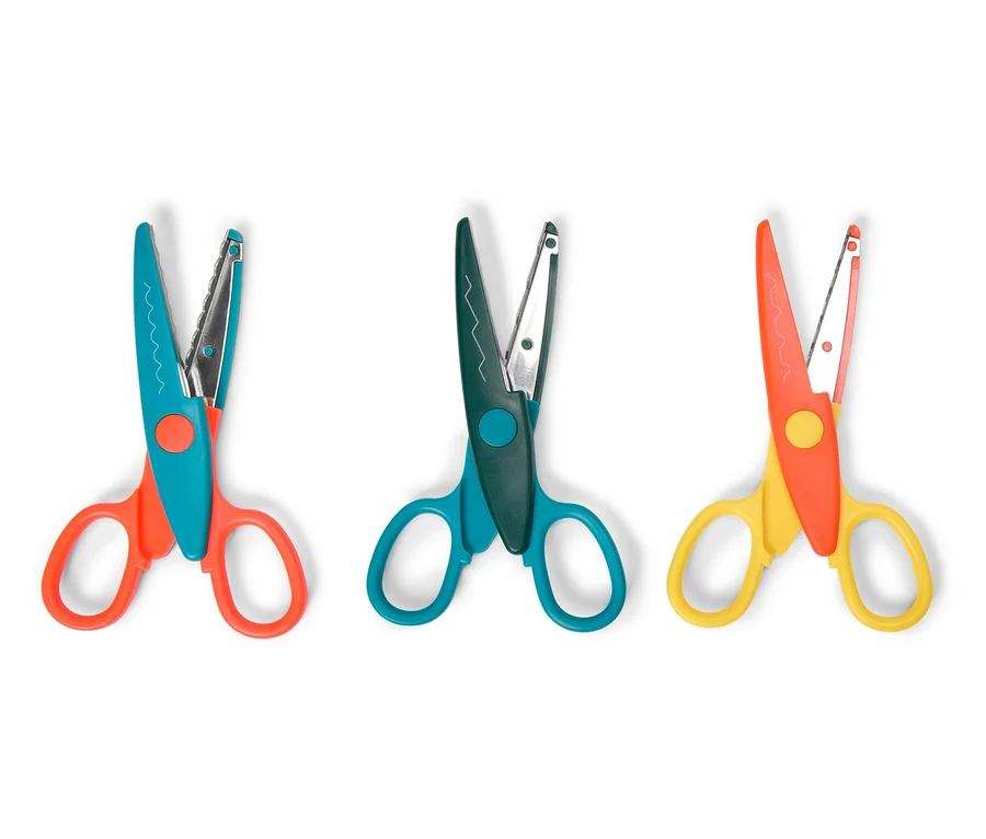 Trois paires de ciseaux avec des manches colorés sont alignées sur un fond blanc.