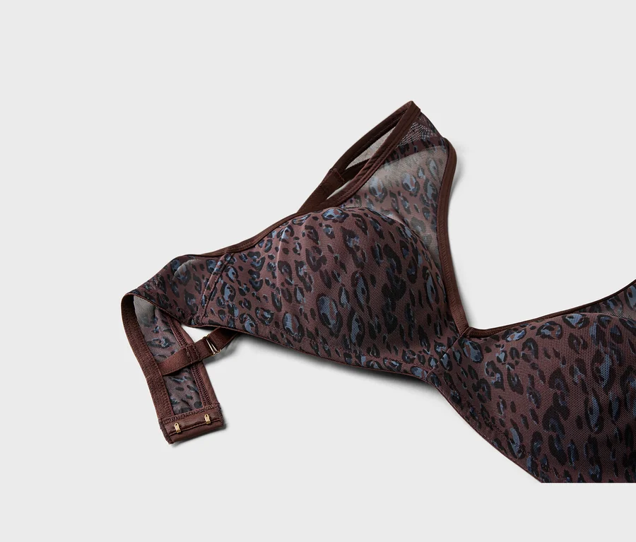 Gros plan d'un soutien-gorge marron avec un motif léopard bleu et noir, en tissu mesh transparent, montrant une bretelle et la bande arrière avec des agrafes.