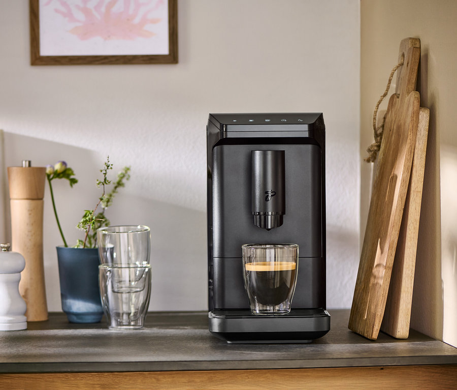Sur un comptoir de cuisine, une machine à café noire « Esperto mini » prépare du café dans un verre.