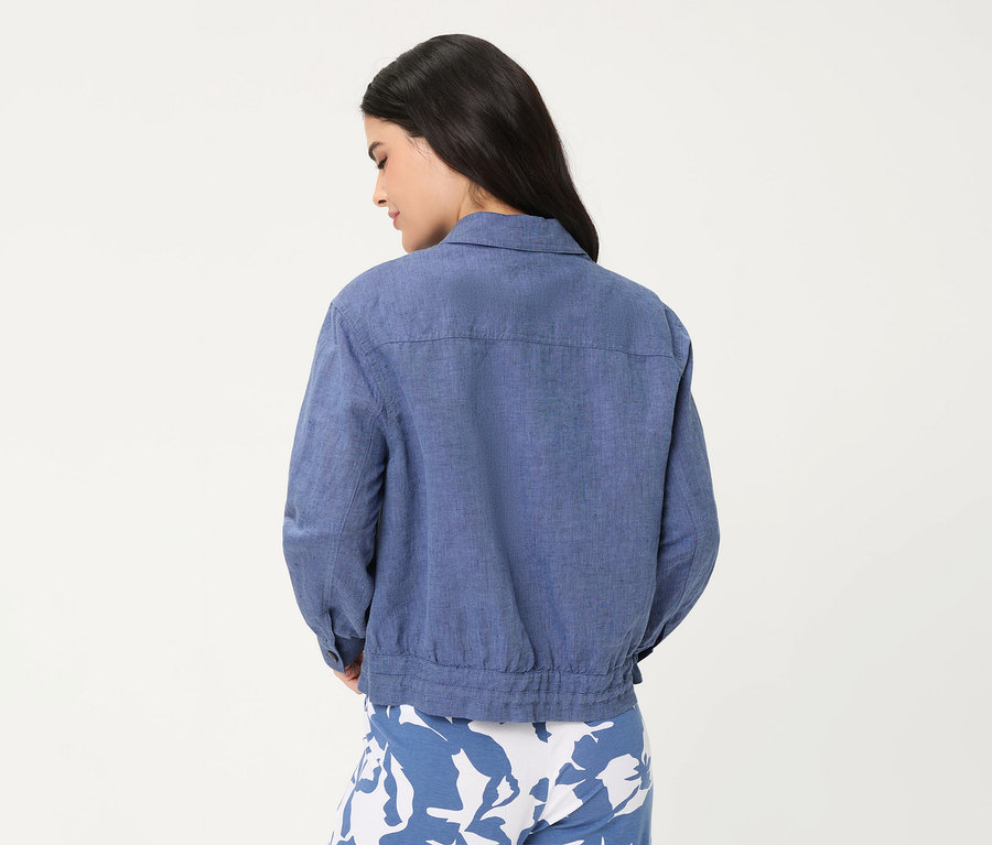 Femme de dos, portant une veste en jean Olsen bleue et un pantalon à motifs bleu et blanc.