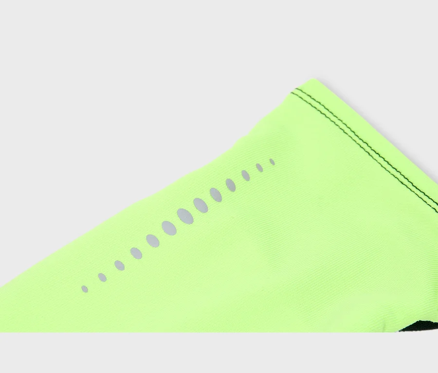 Gros plan sur un tissu vert fluo avec une rangée de points gris réfléchissants, de taille décroissante, et des coutures noires le long du bord supérieur.