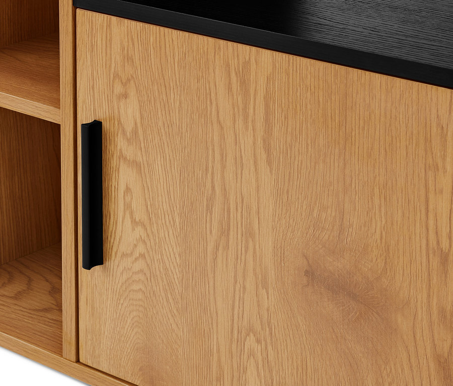 Gros plan d'une armoire en bois clair avec une poignée noire sur la porte. À gauche se trouvent des étagères en bois ouvertes, et la surface supérieure est noire.