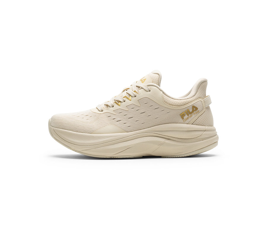 Une seule chaussure de sport beige clair avec une semelle épaisse et une tige en maille. Les logos dorés « FILA » sont sur le côté et la languette.