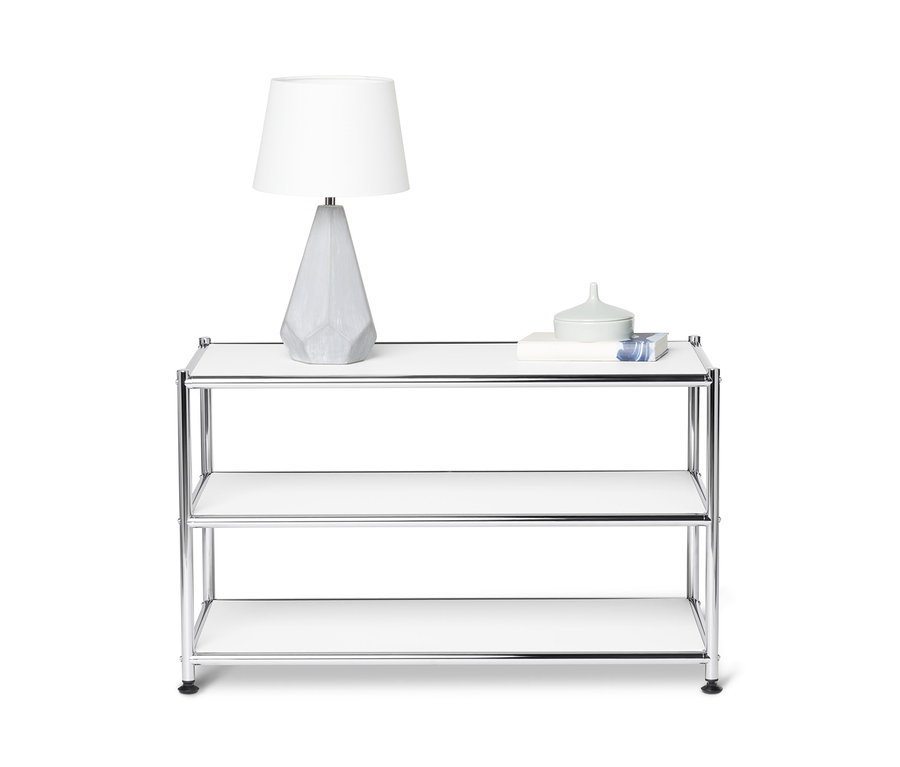 Sur l'étagère supérieure d'une table basse en métal « CN3 », sont posées une lampe et des décorations.
