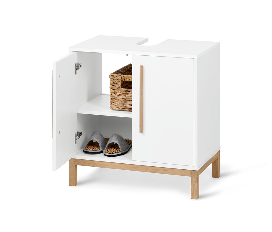 Un meuble sous vasque «	Eklund	» blanc ouvert avec un panier et des chaussons à l'intérieur.