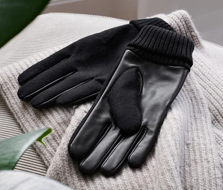 Des gants en cuir noirs reposent sur un pull.