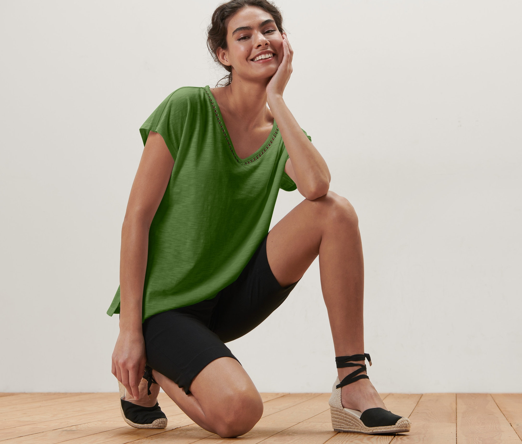 Femme agenouillée portant un haut vert avec empiècement au crochet et un short de cycliste noir.