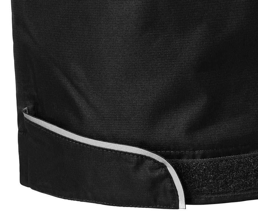Gros plan sur un pantalon de pluie noir avec bordure réfléchissante et fermeture velcro.
