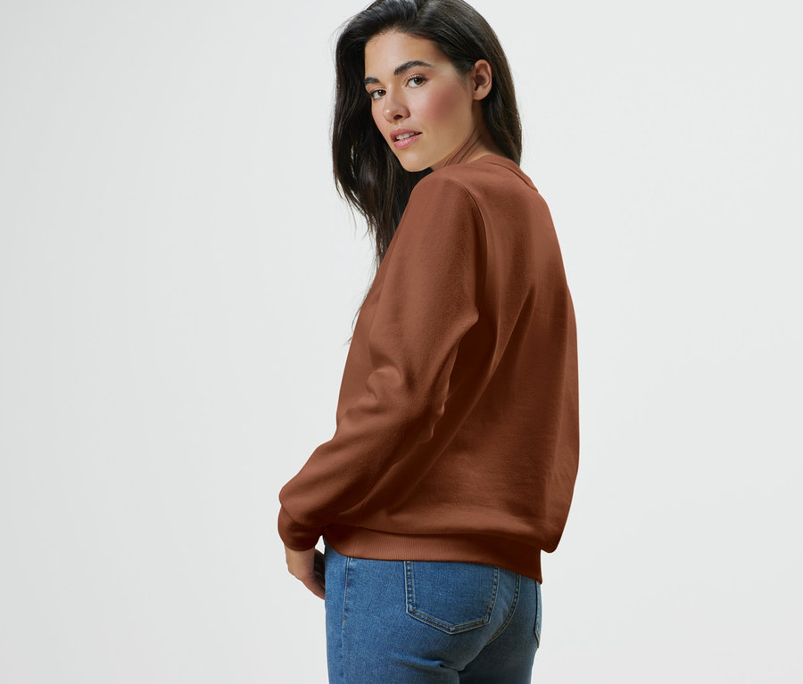 Femme regardant par-dessus son épaule portant un sweat-shirt et un jean.