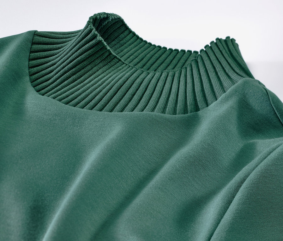 Détail d'un sweatshirt vert avec col montant.