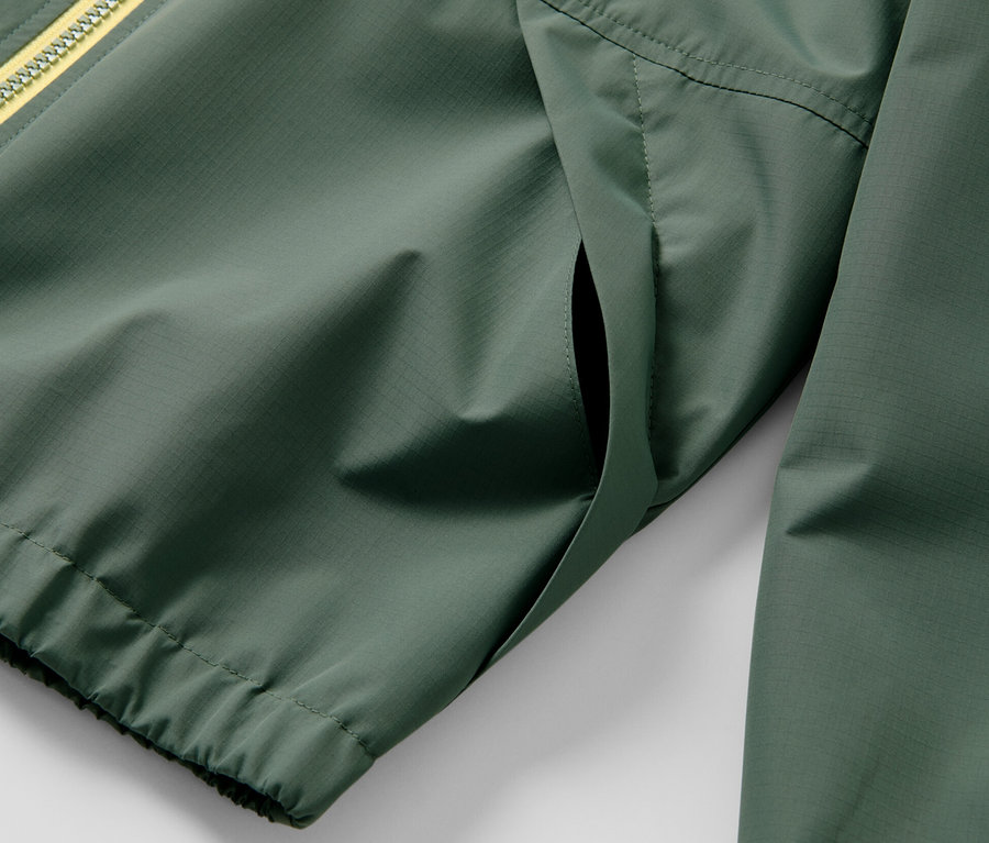 Vue détaillée d'une veste de sport fonctionnelle verte pour enfant avec une fermeture éclair jaune.