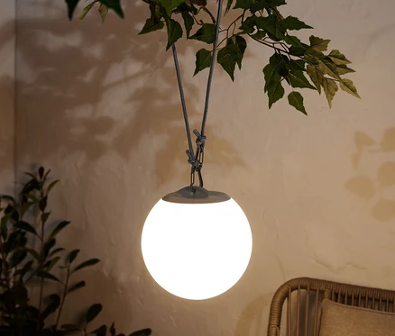 Une lampe avec balancier à pile LED est suspendue à une branche d'arbre.