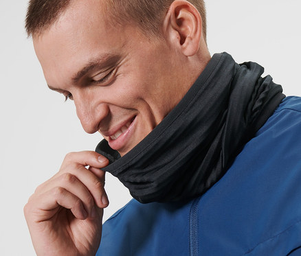Un homme ajuste un foulard multifonction noir autour de son cou.