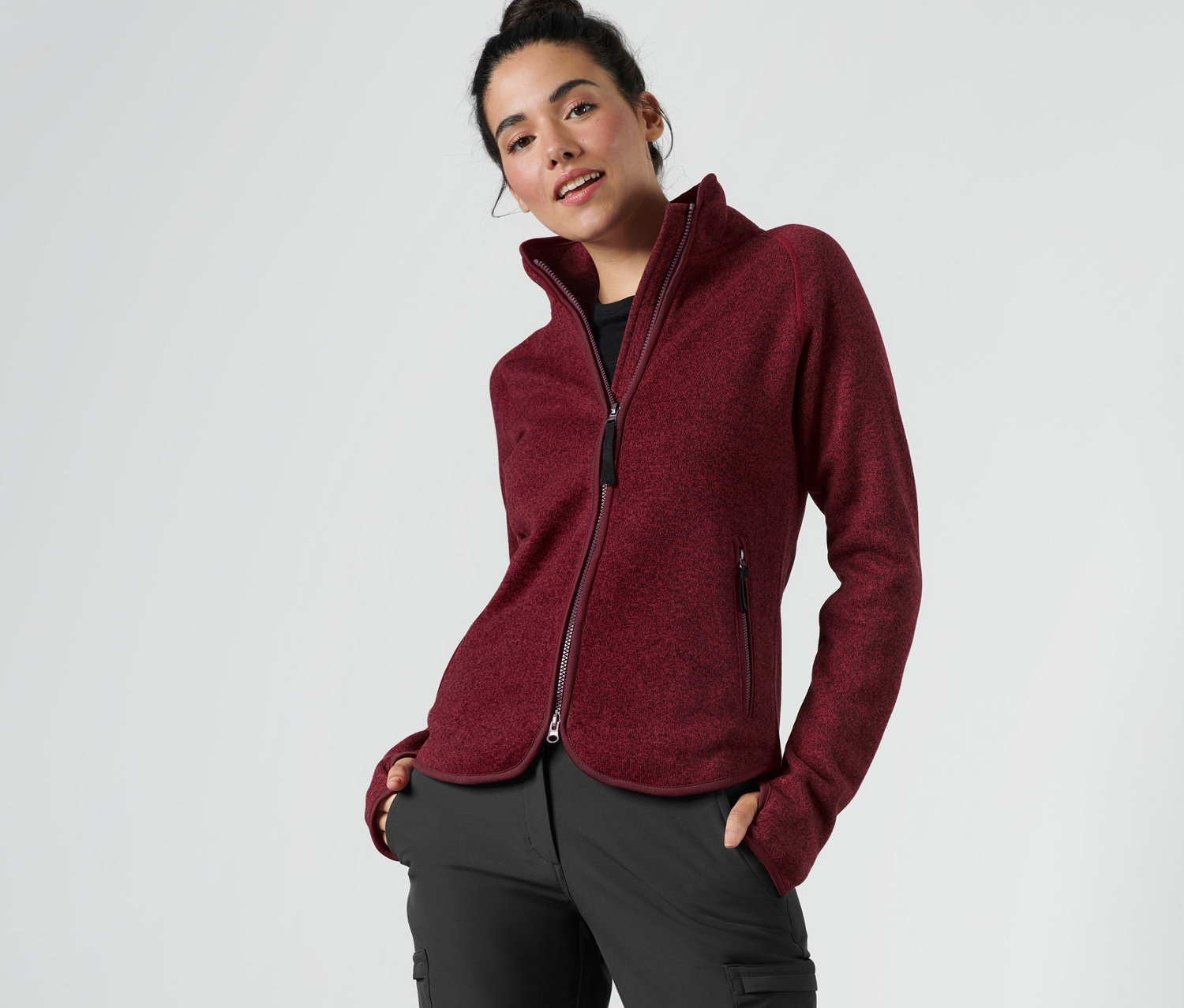 Femme posant dans une veste en maille polaire rouge foncé.