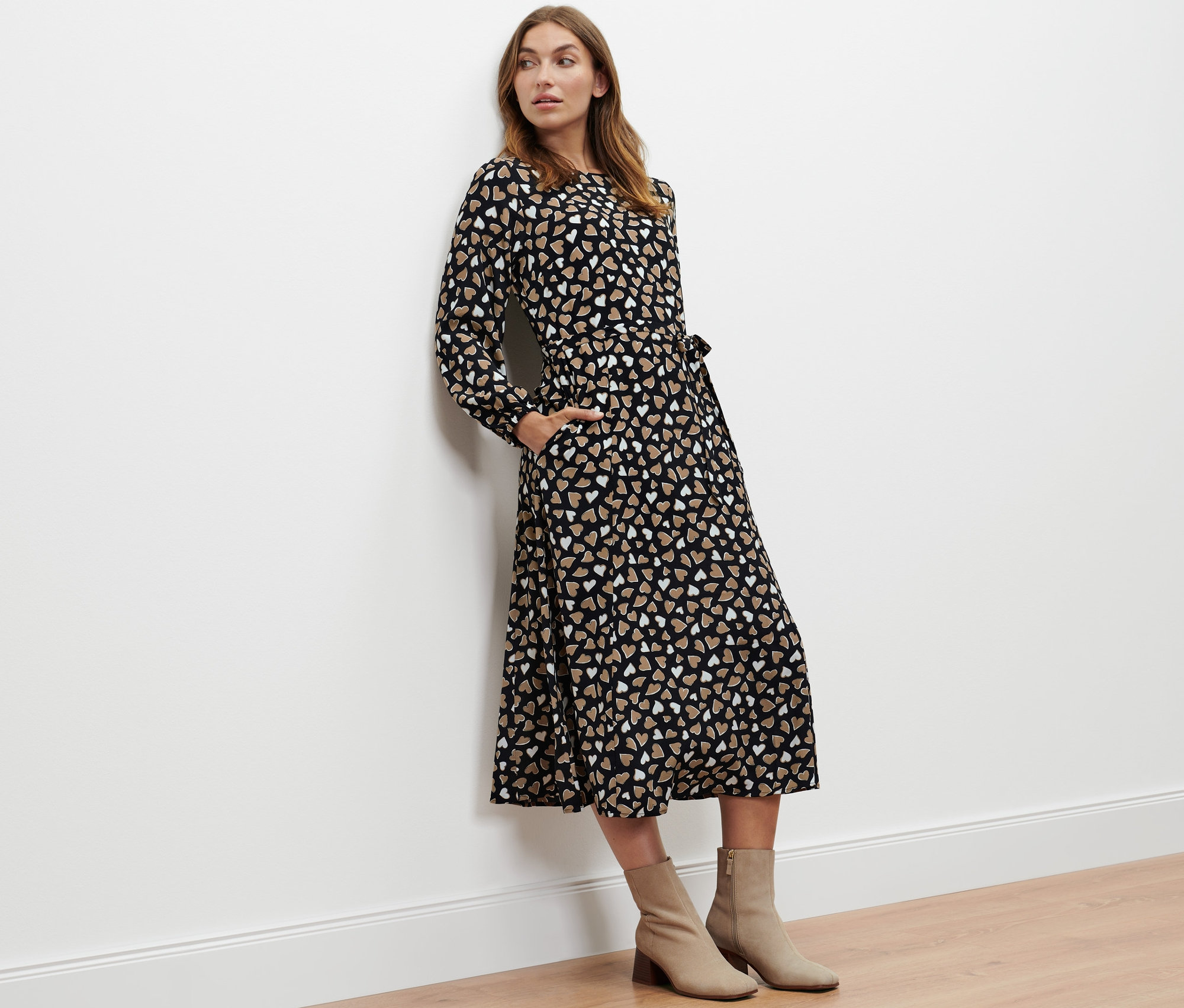 Femme posant en robe tissée à imprimé intégral et bottines beiges.