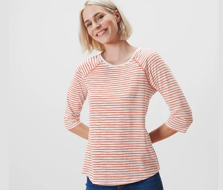 Une femme blonde porte un t-shirt manches 3/4 à rayures et un jean.
