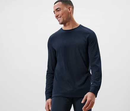 Un homme souriant porte un t-shirt à manches longues bleu marine avec de la laine certifiée RWS.
