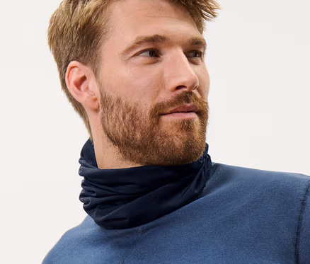 Un homme aux cheveux bruns porte un foulard multifonction bleu en laine certifiée RWS et un haut bleu.