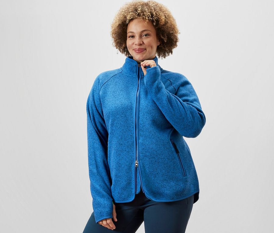 Femme fermant une veste en polaire tricotée bleue et portant un pantalon jazz thermique.