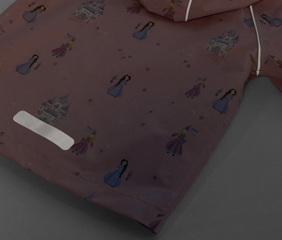 Gros plan sur une veste de pluie pour enfant avec des motifs de princesses et de châteaux.