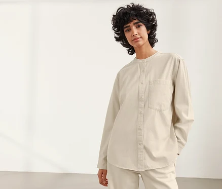 Femme posant dans une blouse beige NAH/STUDIO en coton durable.