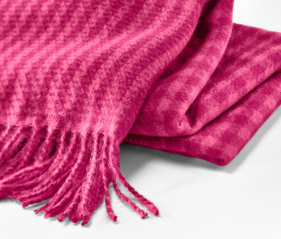 Gros plan sur une écharpe tissée à franges framboise.