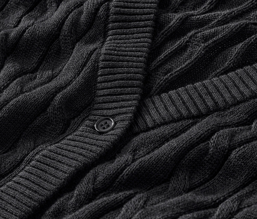 Gros plan sur un cardigan noir en maille fine à motif torsadé.