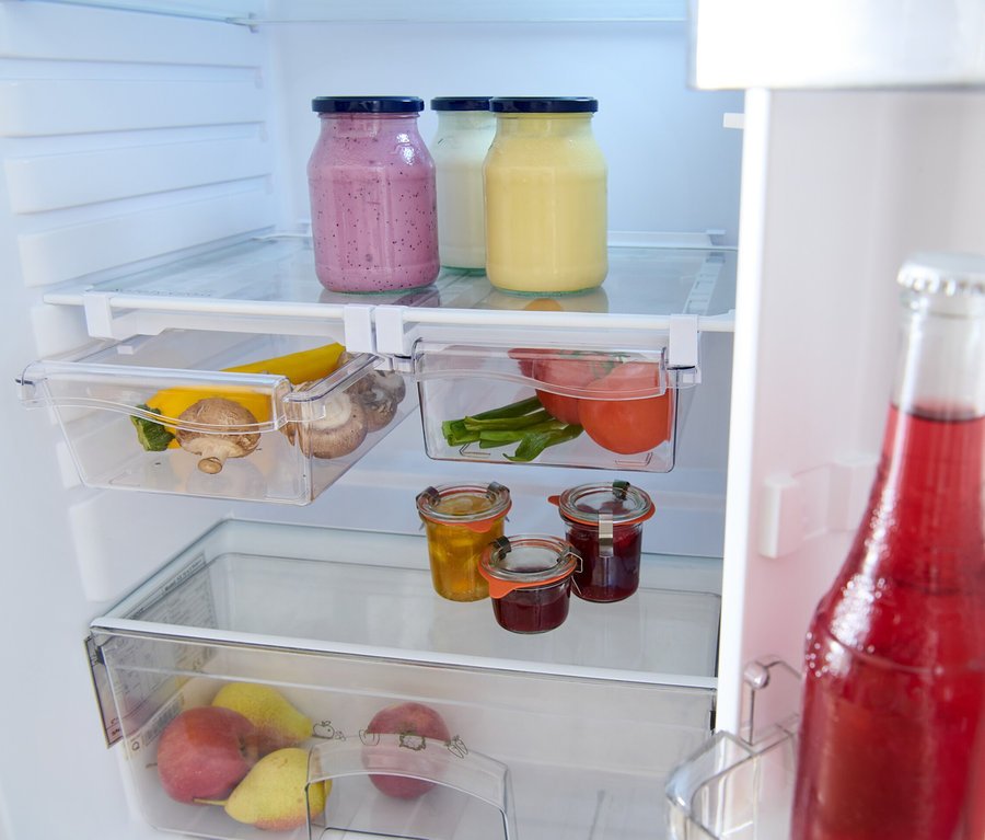 Dans le réfrigérateur, il y a trois bocaux avec couvercles, dont deux remplis et un vide. De plus, il y a 2 compartiments de réfrigérateur extensibles, un avec des tomates et un avec des champignons et des courgettes.
