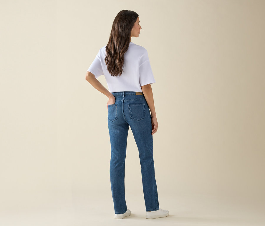 Une femme, dos à la caméra, porte un jean, un t-shirt et des baskets.
