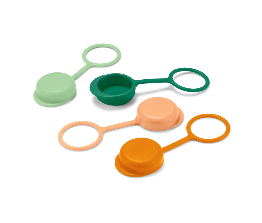 Quatre bouchons de bouteille verts, vert foncé, pêche et orange sont posés sur une surface blanche.