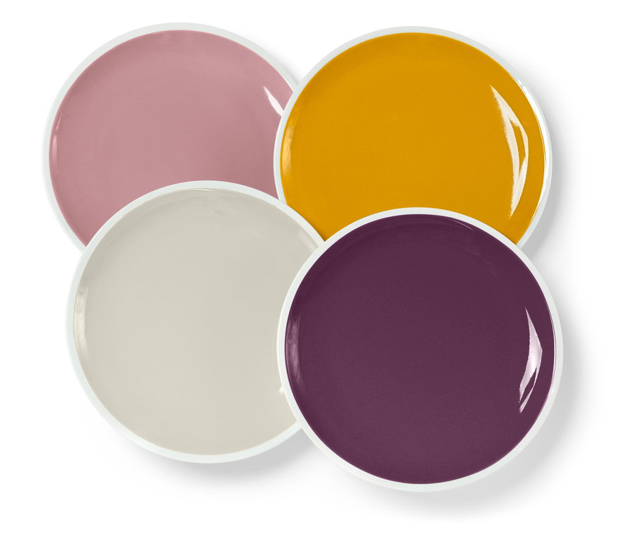Quatre assiettes de différentes couleurs (rose, jaune, beige et violet) avec un bord blanc empilées les unes sur les autres.
