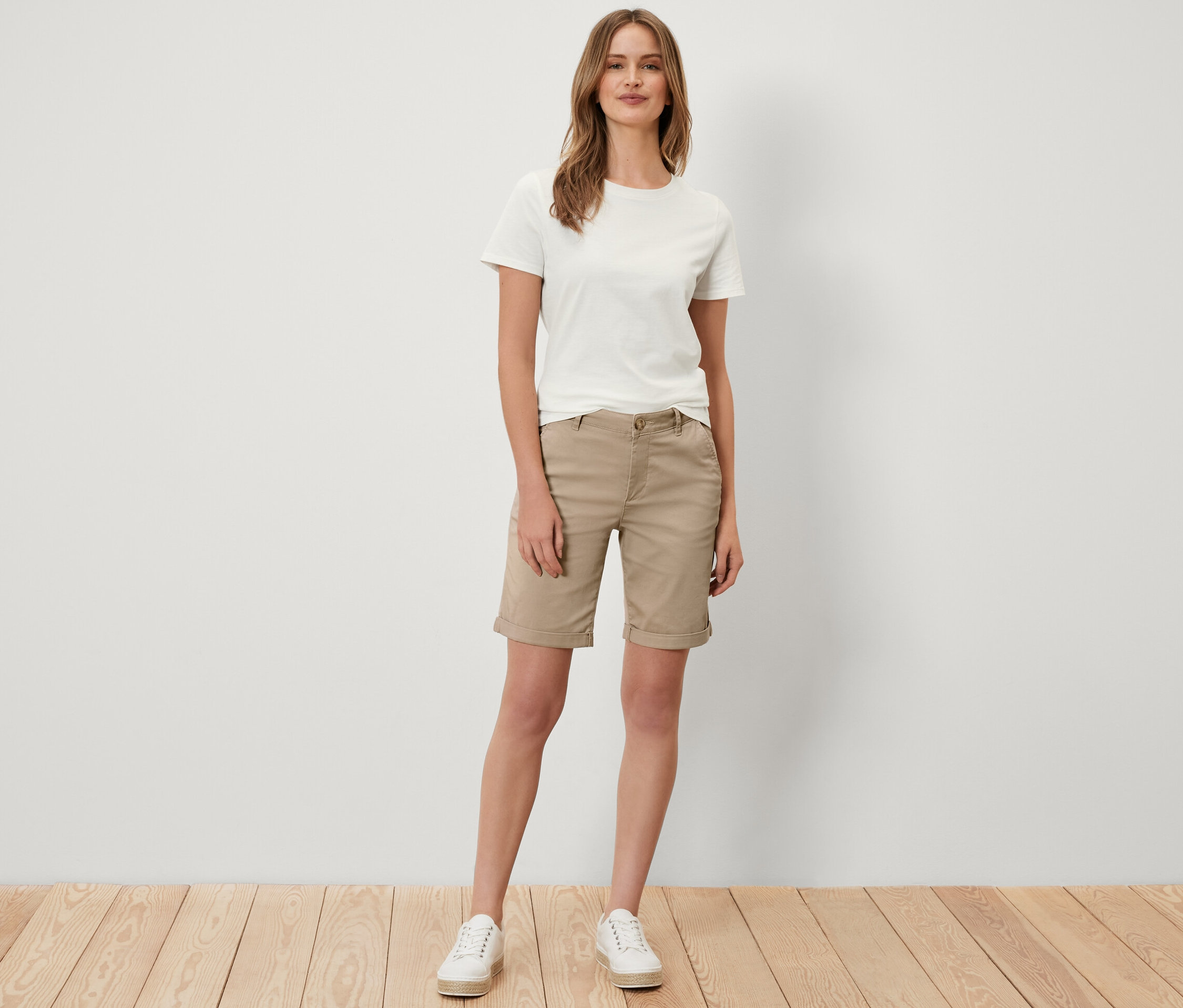 Une femme debout porte un short chino beige.